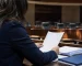 Profesional revisa un informe en un salón legislativo genérico.