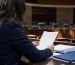 Profesional revisa un informe en un salón legislativo genérico.